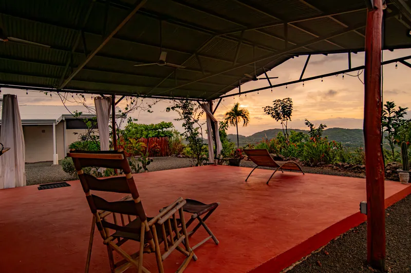 The shaded deck of the yoga studio with loungers looking toward a soft sunset