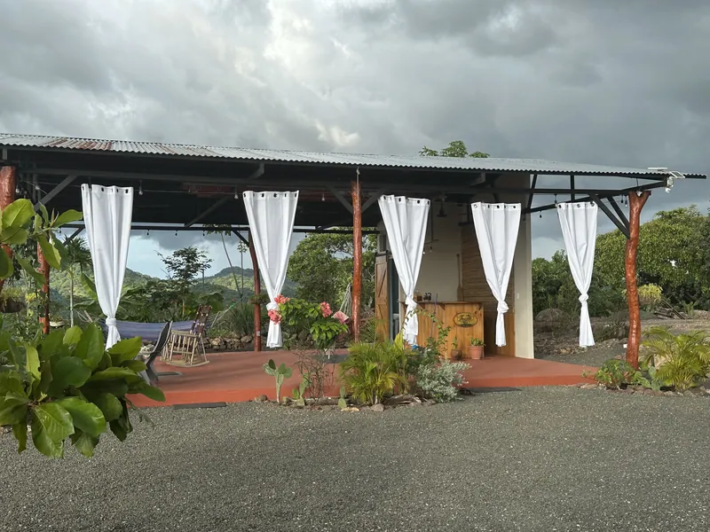 The open-air yoga studio with flowing white curtains under a cloudy sky