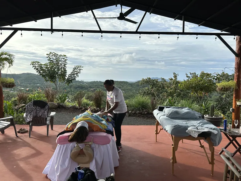 A guest enjoying a massage in the open-air yoga studio above the treetops